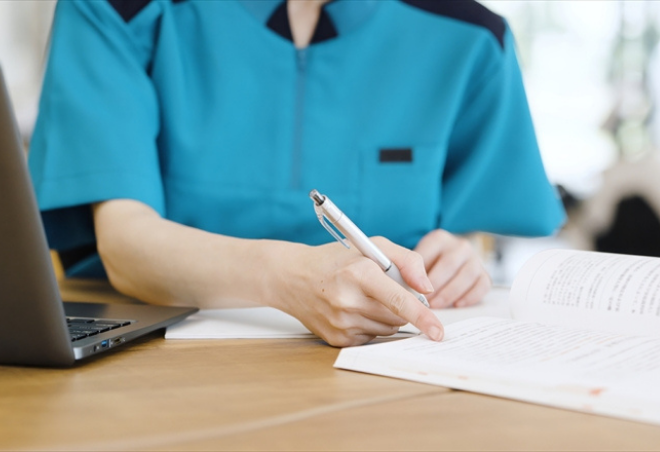 介護士が運営基準の勉強をパソコンと資料を使って学んでいる様子